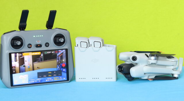 DJI Mini 4 Pro placed alongside the DJI RC 2 remote controller and the 3-way battery charging hub