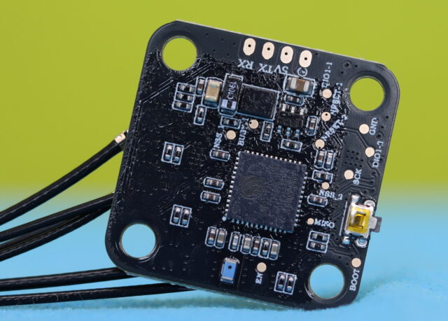 Close-up view of the Radiomaster DBR4 receiver showing solder pads and labeled pinout for wiring.