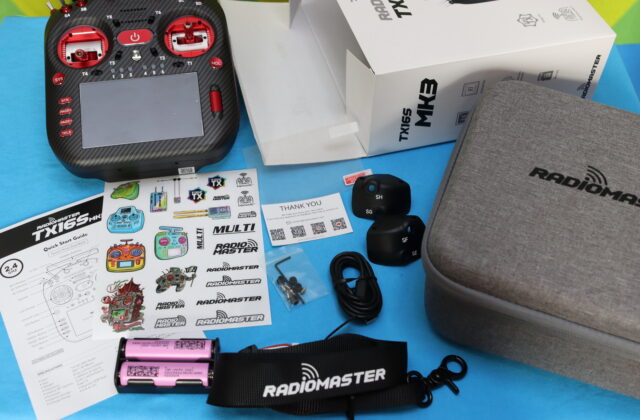 RadioMaster TX16S MK3 radio transmitter during unboxing, showing the controller and packaging contents on a desk.