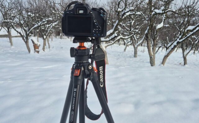 K&F CONCEPT 63-Inch Tripod holding a Canon DSLR camera, set up in a snowy field for outdoor photography.