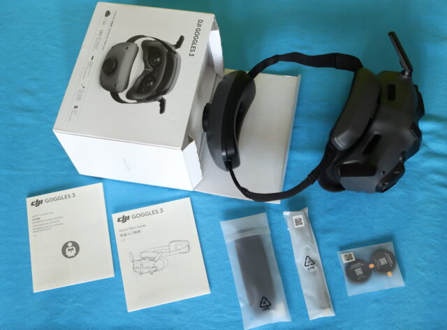 DJI Goggles 3 unboxing showing contents laid out including headset, battery pack, and cables