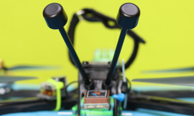 Pair of stock Walksnail Avatar GT2 antennas placed next to the GT2 video transmitter, showing the compact design and MMCX connectors.