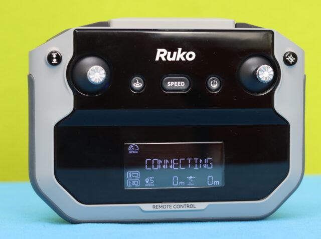Ruko F11PRO 2 Plus remote controller shown in close-up, featuring dual control sticks, smartphone holder, antenna system, and flight control buttons for drone operation.