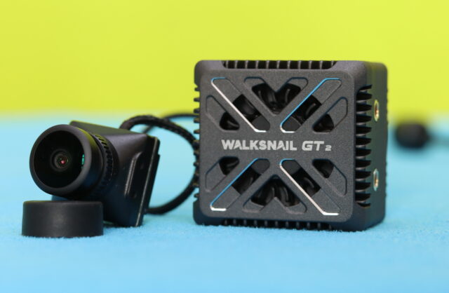 Close-up view of the Walksnail Avatar GT2 digital FPV system, highlighting the VTX housing, cooling design, antenna connectors, and camera wiring details.